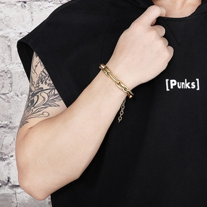 Close-up of a gold thick chain pig nose bracelet worn by a male model on a street background