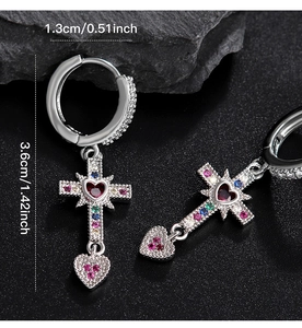 Macro shot of silver cross earrings with colorful rhinestones and heart pendants