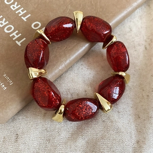 Detailed shot of glossy red acrylic beads with glitter and gold metal spacers on jewelry