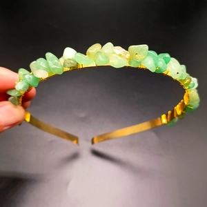 Detailed close-up of handmade gold metal headband with green raw crystal stones