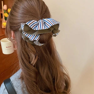 Détail d'un chouchou noeud en tissu rayé multicouche porté sur une coiffure de dos élégante