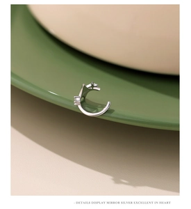 Macro detail of silver S925 star ear cuff with sparkling square zircon on ceramic tray