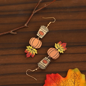 Macro view of wooden Halloween earrings with pumpkin, maple leaf and ghost drop charms