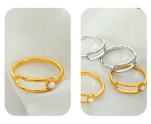 Detail of gold and silver open rings with pearl accent on soft white fabric background