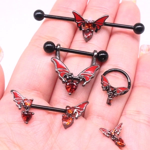Close-up of black metal piercing set with red enamel bat wings and heart pendants