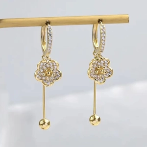 Elegant gold flower tassel earrings with crystals on a jewelry display stand