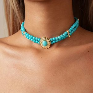 Detail of double-layer turquoise beaded necklace with gold crystal floral pendant on model