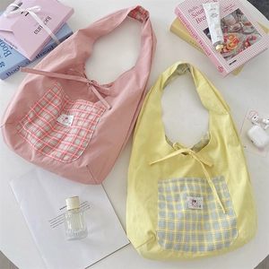 Detail of canvas tote bags with checkered pockets and bow-tie straps in pastel pink and yellow