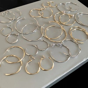 Macro display of minimalist twisted metal hoop earrings in gold and silver finishes