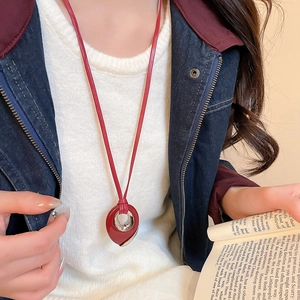Detailed close-up of a red teardrop pendant necklace on a leather cord worn by a model