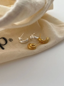 Close-up of minimalist C-shaped stacked fluid earrings in gold and silver finish