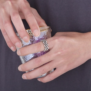 Minimalist silver stainless steel ring with watch strap texture worn by a model
