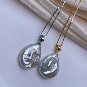 Detailed macro of gold and silver baroque pearl pendants with iridescent luster and box chains
