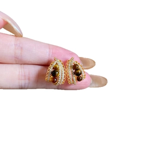 Elegant gold feather earrings with brown tiger eye stones and sparkling zircons