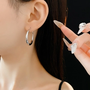 Silver crescent hoop earrings shown on a model with a minimalist high-fashion metal finish