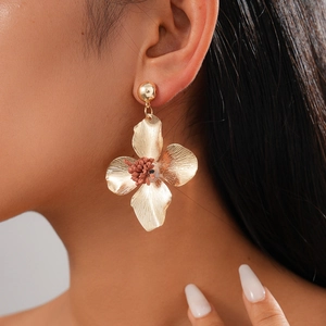 Detailed view of vintage gold flower earrings with red pistil on model