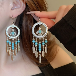Bohemian silver eagle earrings with turquoise stones and feather tassels on a model