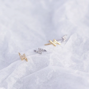 Macro view of lightning bolt stud earrings in gold and silver with inlaid diamonds