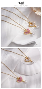 Detail of heart-shaped zircon and pearl pendant on a gold chain over white silk
