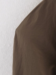 Detail of dark brown trench coat fabric texture and premium stitching craftsmanship