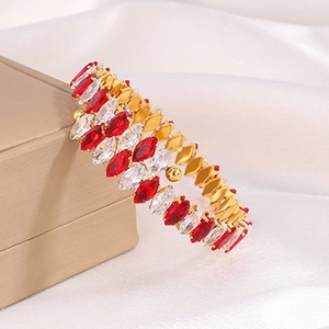 Macro detail of gold-tone titanium bangle with red zircon stones on a jewelry box