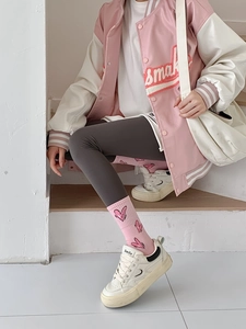 Close-up of pink crew socks with heart patterns worn with grey leggings and sneakers