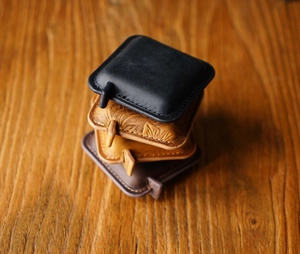 Detailed close-up of stacked handmade crazy horse leather mini measuring tapes on wood