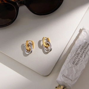 Detail of interlocking gold and silver hoop earrings on a stylish modern vanity background