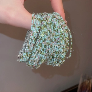Detailed close-up of crystal elastic bracelets in light blue and green with diamond accents