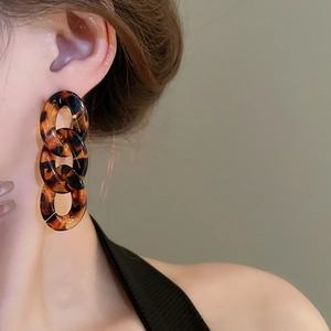 Close-up of leopard tortoise shell acrylic chain earrings worn by a female model