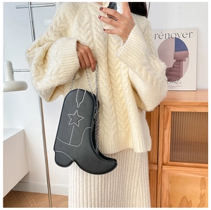 Detailed view of creative black boot-shaped crossbody bag with white star stitching