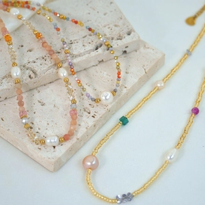 Detailed macro of handmade freshwater pearl necklaces with colorful natural gemstones