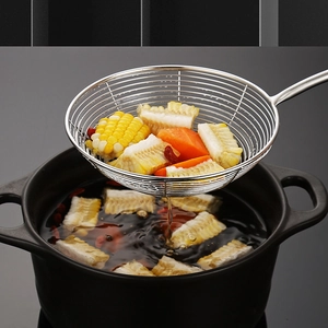 Stainless steel slotted spoon with wooden handle lifting corn and carrots from a pot