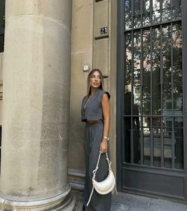 Detail of grey pinstripe vest and wide-leg trousers set with a white shoulder bag