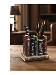 Detail of vintage book-shaped resin pen holder with gold embossed spines on wooden desk