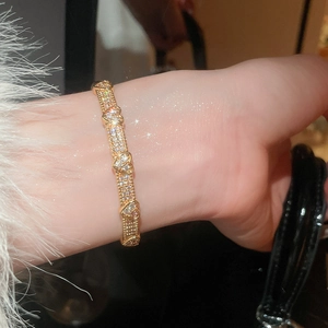 Close-up of gold plated heart-shaped bangle with micro-paved zircons and bead edge detail