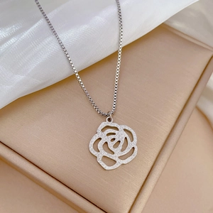 Vue rapprochée du pendentif rose évidé en argent sur une chaîne sur tissu en soie