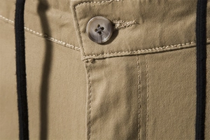 Macro detail of khaki cargo pants featuring amber buttons, black drawstring and twill fabric
