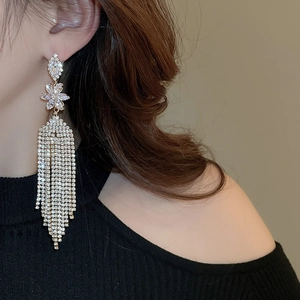 Macro view of long tassel earrings with sparkling crystals and a floral top design
