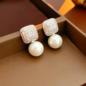 Detail of square zircon studs with round white pearls in a brown jewelry box
