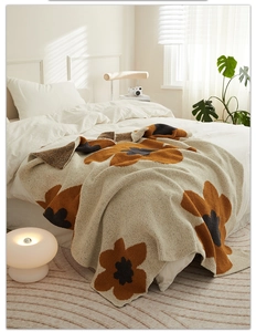 Close-up of knit floral blanket with sun flower pattern on white bedding in warm light
