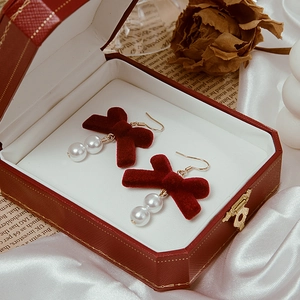Detail shot of burgundy velvet bow earrings with double pearls in a jewelry gift box
