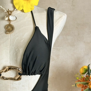 Detail of black bikini top with a large gold metal ring and a shell necklace accessory