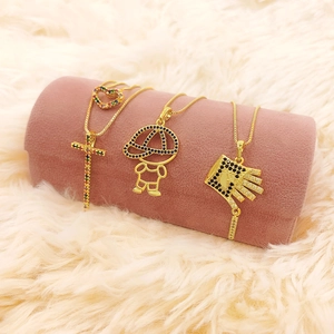 Colliers dorés avec pendentifs croix et cœur sur support en velours rose chic
