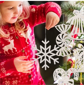 Close-up of white glittery Christmas snowflake and bell ornaments being hung on a tree