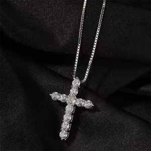 Minimalist silver cross necklace with sparkling diamonds on a black silk background