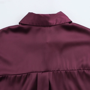Close-up of wine red satin shirt collar and pleated back detail with silky texture