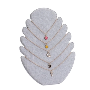 Golden necklace set with clover, heart, and moon pendants on a velvet jewelry display