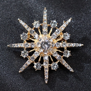 Macro shot of luxury golden starburst brooch with sparkling rhinestones on grey background