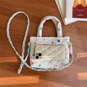 Detailed top view of a white quilted phone bag with colorful dots and woven straps
